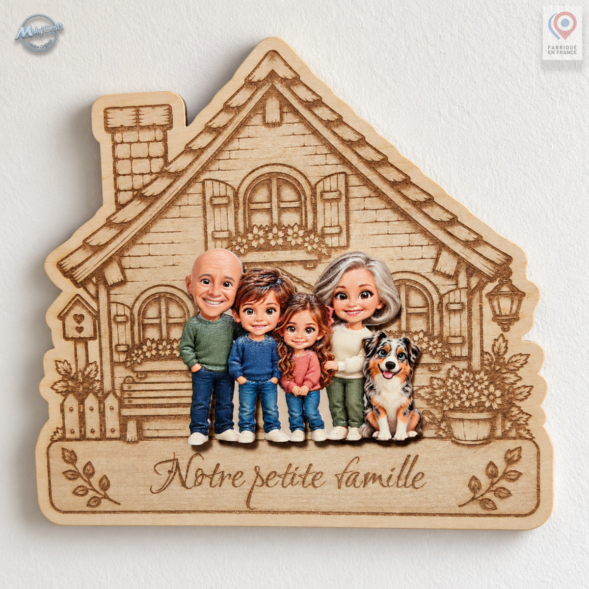 Vue rapprochée d’une maison de famille personnalisée en bois gravé, accrochée sur un mur blanc. Deux grands-parents, un garçon, une fille et un chien sont réunis en portraits chibi colorés en relief. L’inscription Notre petite famille est gravée sous le groupe, avec des motifs de feuilles de chaque côté.
Close-up of a personalized wooden family house hanging on a white wall. Colorful raised chibi portraits depict two grandparents, a boy, a girl and a dog. The French inscription Notre petite famille is engra