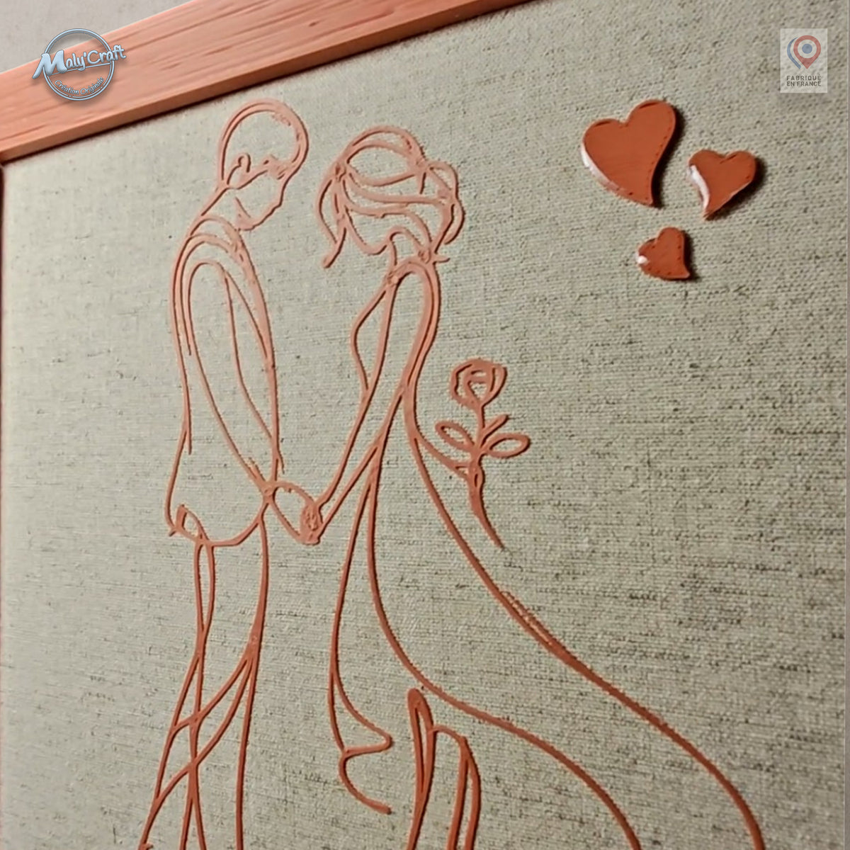 Détail du cadre de mariage personnalisé montrant le couple en dessin linéaire 3D, la trame naturelle du lin et les trois cœurs en relief. Vue rapprochée mettant en valeur la finesse de fabrication et les différentes textures.
Close-up detail of a personalized wedding frame showing the 3D line-art couple, natural linen weave and three raised hearts. The close view highlights the fine craftsmanship and contrasting textures.