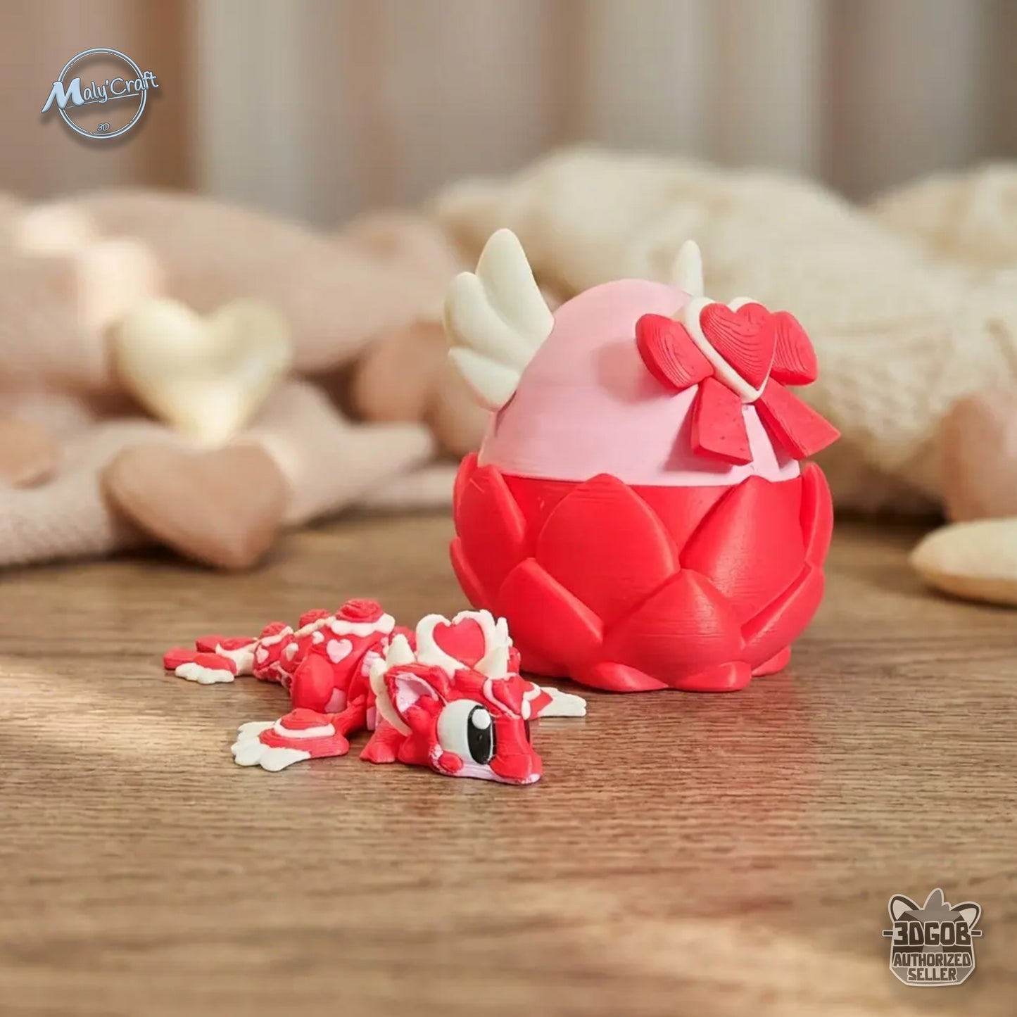 Figurine dragon articulé rouge et blanc avec détails de cœurs sur le corps, création éco-responsable en amidon de maïs. Il est présenté à coté de son oeuf ouvrable