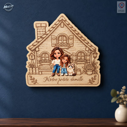 Maison de famille personnalisée en bois clair gravé, ornée des portraits chibi d’une mère, de sa fille et de leur chat. L’inscription Notre petite famille apparaît sous les personnages. Cette décoration murale est présentée sur un mur bleu nuit, au-dessus d’une console en bois avec un vase écru.
Personalized wooden family house plaque featuring colorful chibi portraits of a mother, her daughter and their cat. The French inscription Notre petite famille is engraved beneath the figures. The plaque hangs on a 