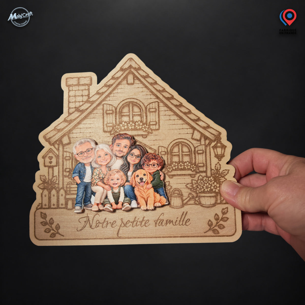 Maison de famille personnalisée photographiée dans une main sur fond noir, montrant le produit et son échelle relative. Le support en bois clair présente une façade gravée, six personnes et un chien réunis en personnages chibi colorés, ainsi que l’inscription Notre petite famille.
Photograph of a personalized wooden family house plaque held in one hand against a black background, showing the physical product and its relative scale. The engraved house features six colorful chibi people and a dog above the Fr