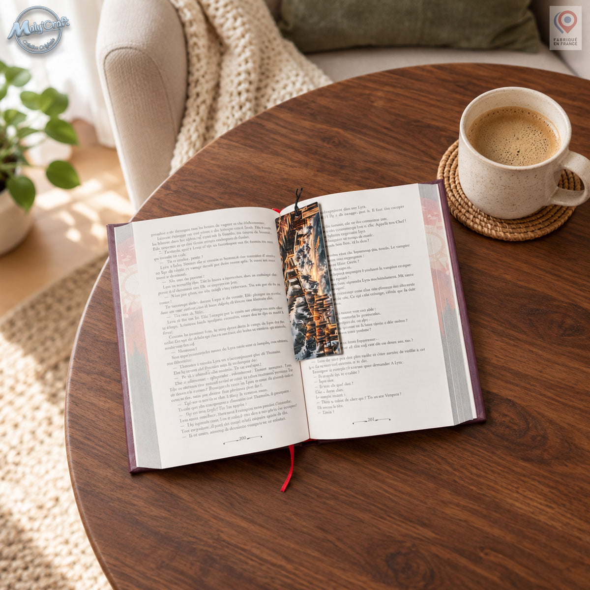 Marque-page dragon posé sur la page droite d’un roman ouvert, près de la reliure. Son illustration fantasy sombre et dorée se détache des pages claires, avec un petit cordon noir dépassant au-dessus. Le livre repose sur une table en bois, près d’une tasse en céramique. Un fauteuil beige, un coussin vert et un plaid clair composent l’arrière-plan.
Dragon bookmark resting on the right-hand page of an open novel near the spine. Its dark fantasy artwork with gold accents contrasts with the pale pages, and a sho