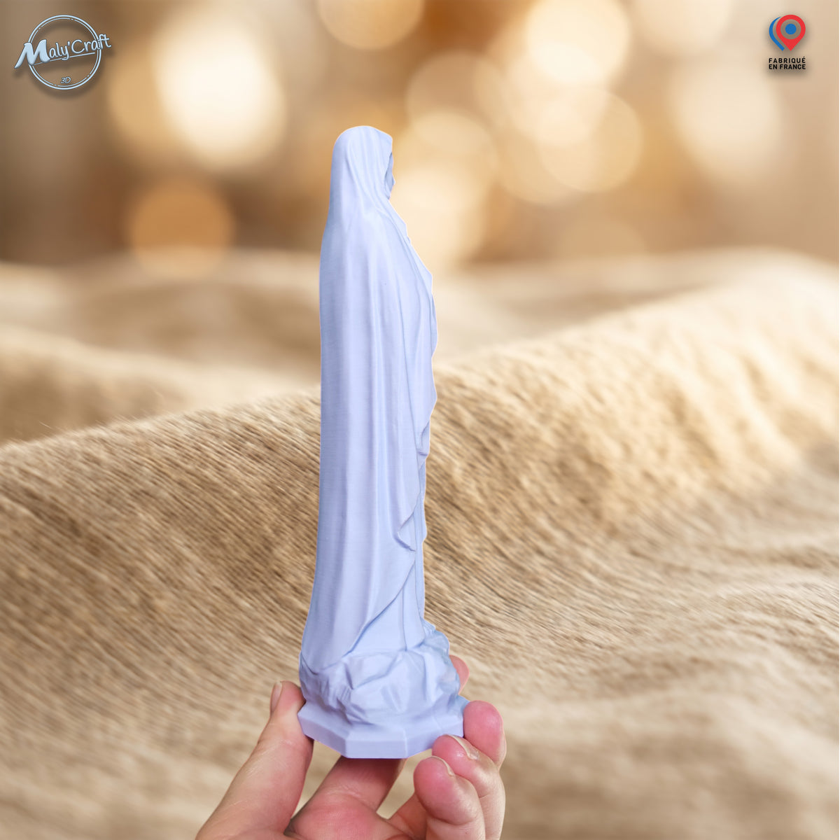 Vue de profil d’une statuette Vierge Marie bleu pastel imprimée en 3D et tenue en main, montrant sa silhouette élancée, le volume du voile, les plis du vêtement et l’épaisseur réelle de la figurine.
Side view of a pastel blue 3D printed Virgin Mary statue held by hand, showing its slender silhouette, veil volume, robe folds and the actual thickness of the figurine.