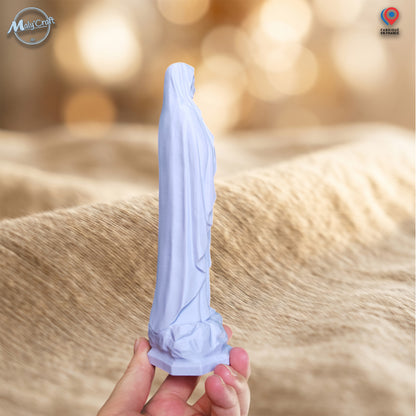 Vue de profil d’une statuette Vierge Marie bleu pastel imprimée en 3D et tenue en main, montrant sa silhouette élancée, le volume du voile, les plis du vêtement et l’épaisseur réelle de la figurine.
Side view of a pastel blue 3D printed Virgin Mary statue held by hand, showing its slender silhouette, veil volume, robe folds and the actual thickness of the figurine.